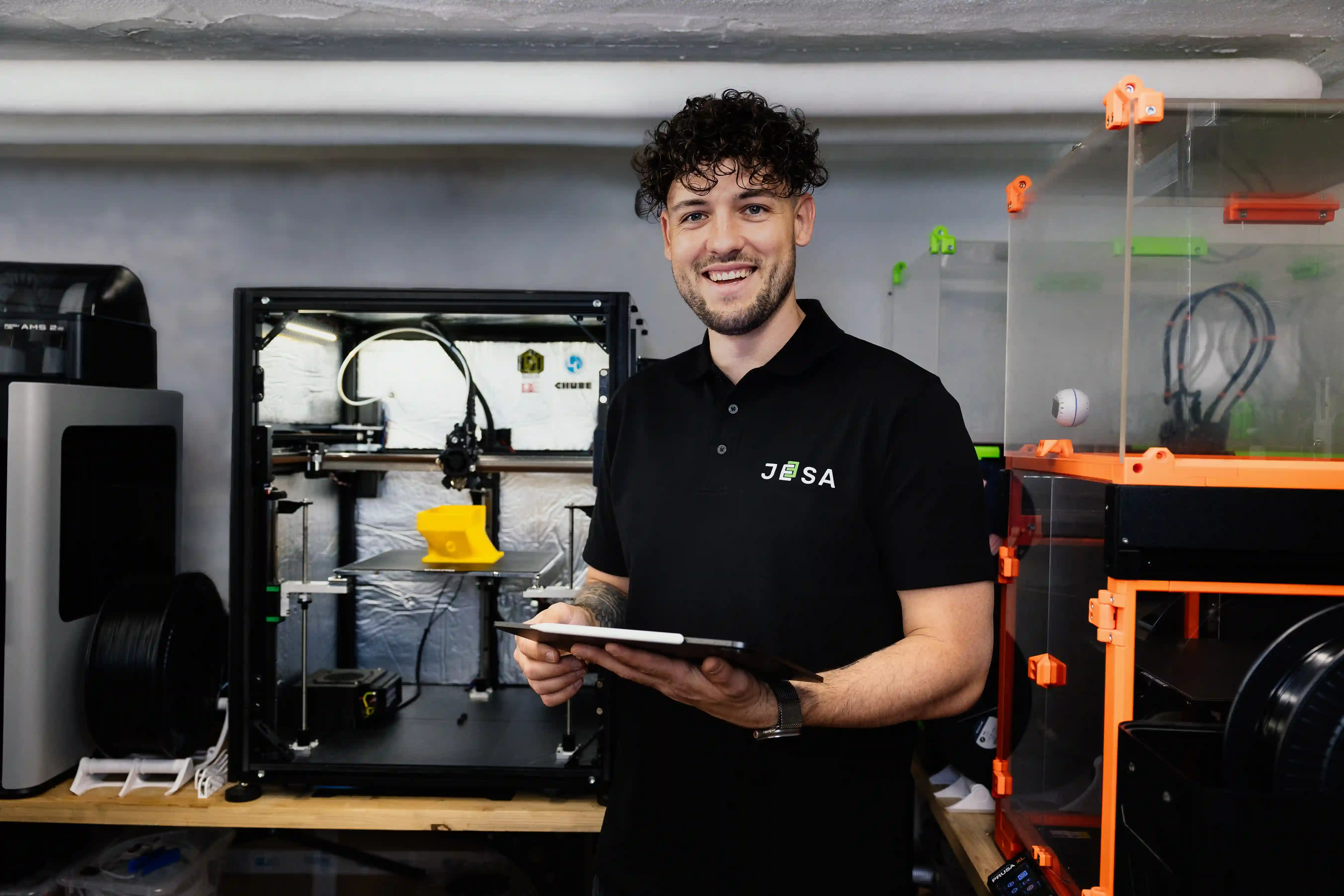 Julian Hof von JESA vor 3D-Druckern in der Werkstatt